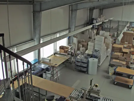 Blick von oben in die Halle mit Arbeitstischen und Kartonagen